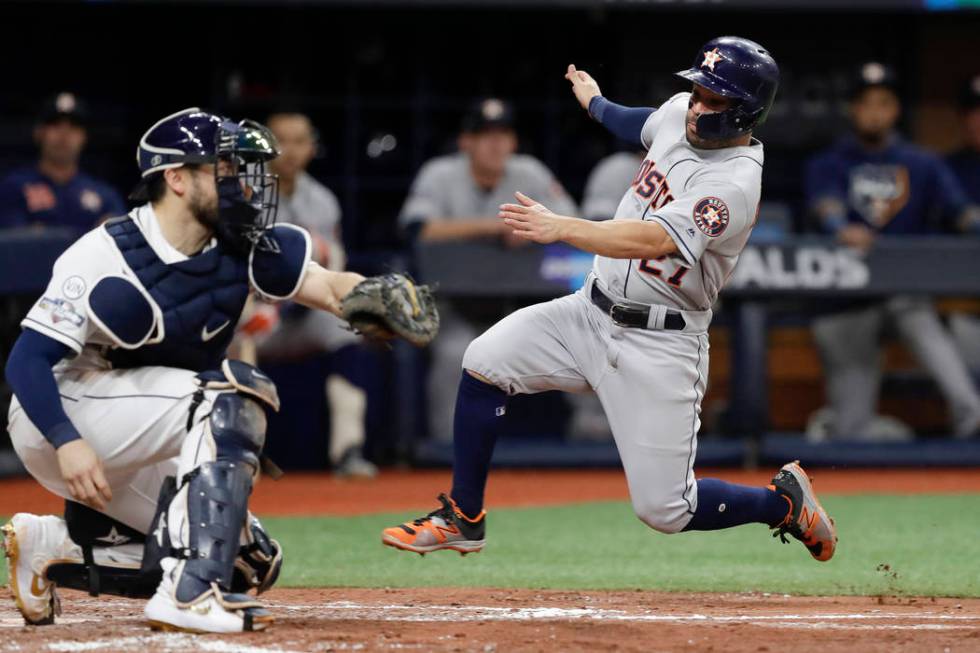 Houston Astros' Jose Altuve, right, heads for home, but is tagged out by Tampa Bay Rays catcher ...