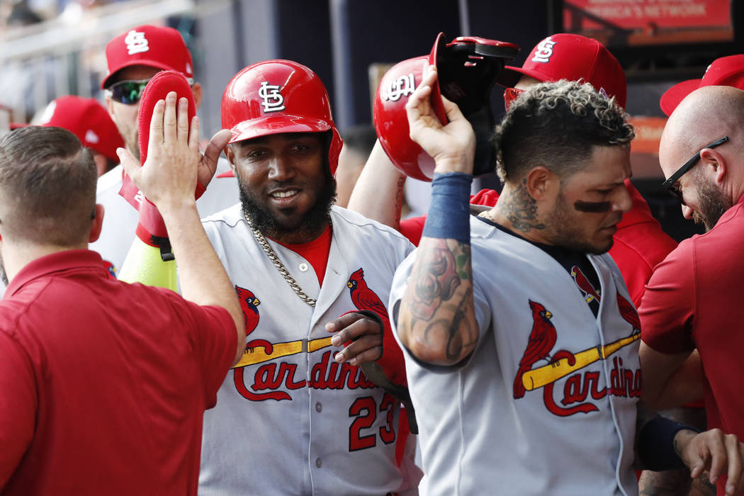 St. Louis Cardinals' Marcell Ozuna, left, and Yadier Molina, are greeted by teammates after sco ...