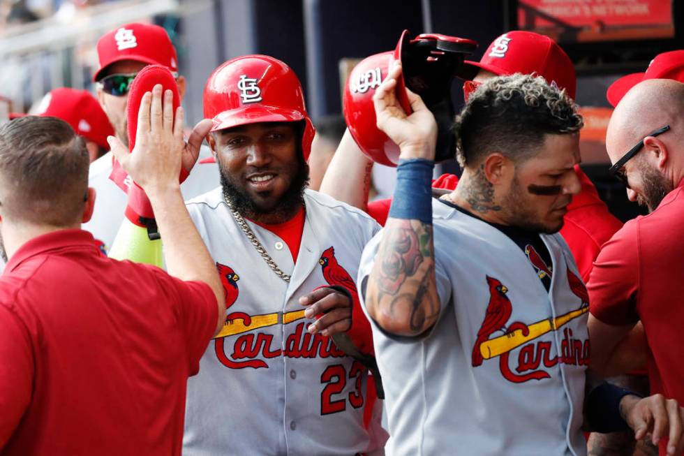 St. Louis Cardinals' Marcell Ozuna, left, and Yadier Molina, are greeted by teammates after sco ...