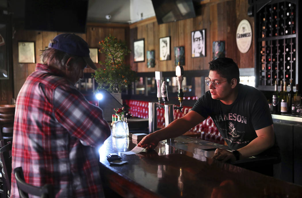 Daniel Ibarra, right, gives a manually written receipt to customer Mark Costales, who paid for ...