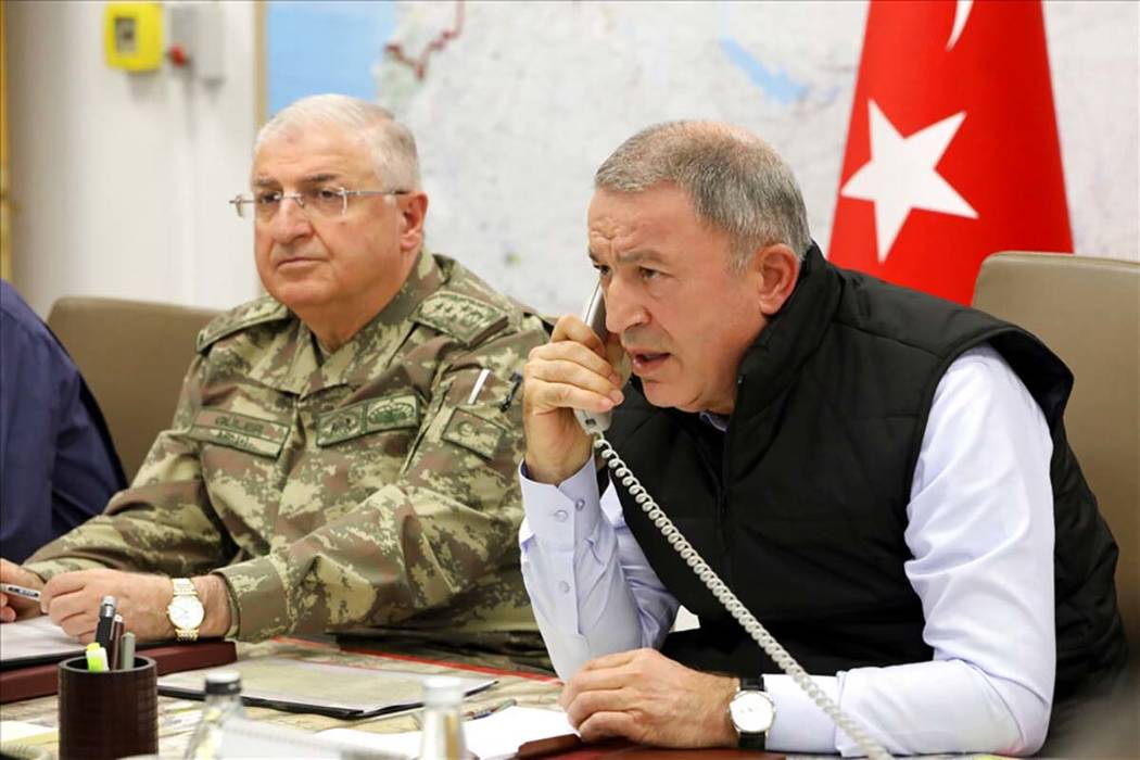 Turkey's Defense Minister Hulusi Akar, right, speaks on the phone alongside Chief of the Genera ...