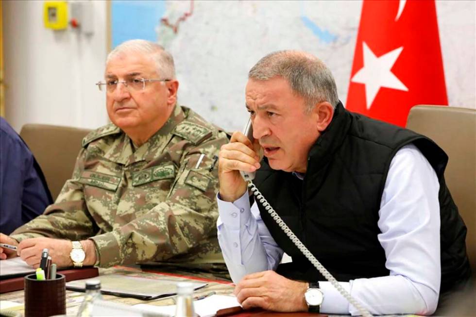 Turkey's Defense Minister Hulusi Akar, right, speaks on the phone alongside Chief of the Genera ...