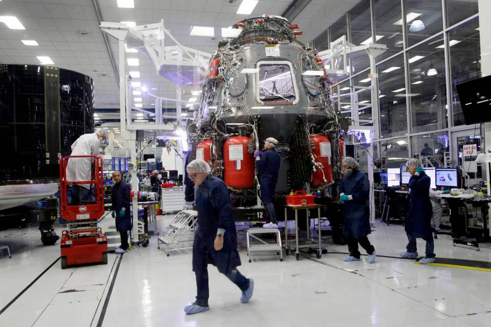 SpaceX employees work on the Crew Dragon spacecraft that will astronauts to and from the Intern ...