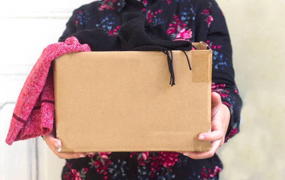 woman holding cardboard box with clothing during clothing drive