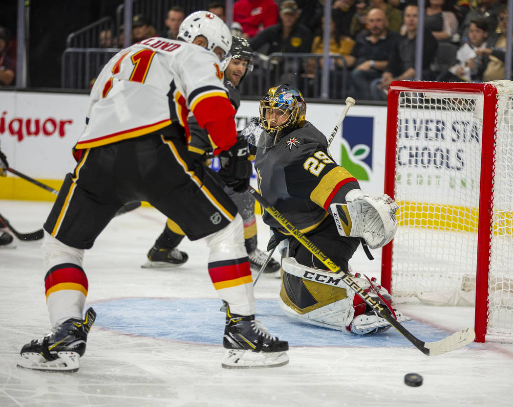 Vegas Golden Knights goaltender Marc-Andre Fleury (29, right) deflects a shot by Calgary Flames ...