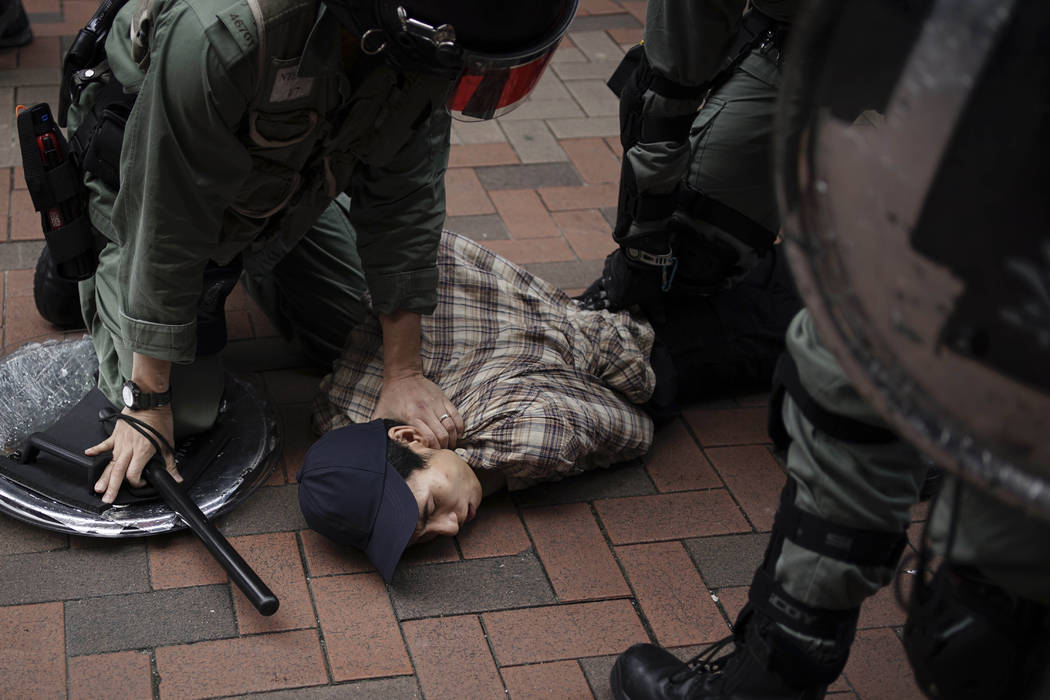 An anti government protester is detained by police at Tseun Wan, Hong Kong, Sunday, Oct.13, 201 ...