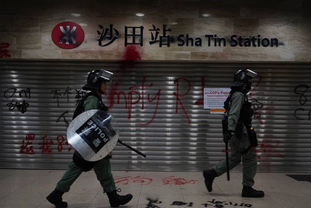 Police walk past graffiti made by protestors at the Sha Tin station in Hong Kong, Sunday, Oct.1 ...