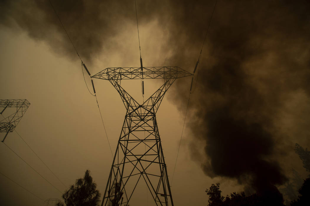 FILE - In this Nov. 9, 2018, file photo, smoke billows around power transmission lines as the C ...