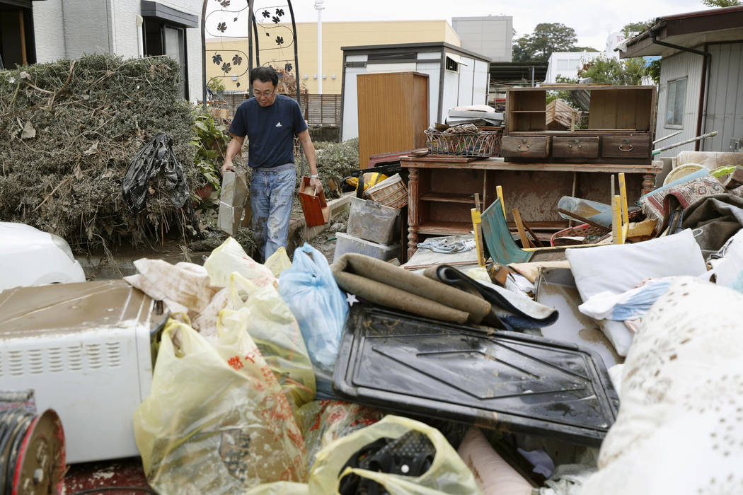 A man carries household goods out of a flooded house in Motomiya, Fukushima prefecture, Japan T ...