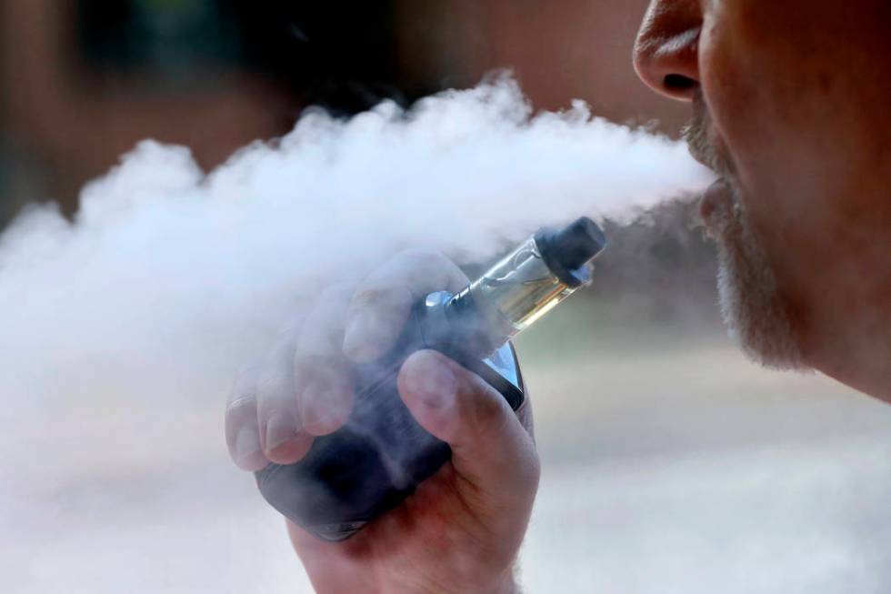 In an Aug. 28, 2019, file photo, a man exhales while smoking an e-cigarette in Portland, Maine. ...