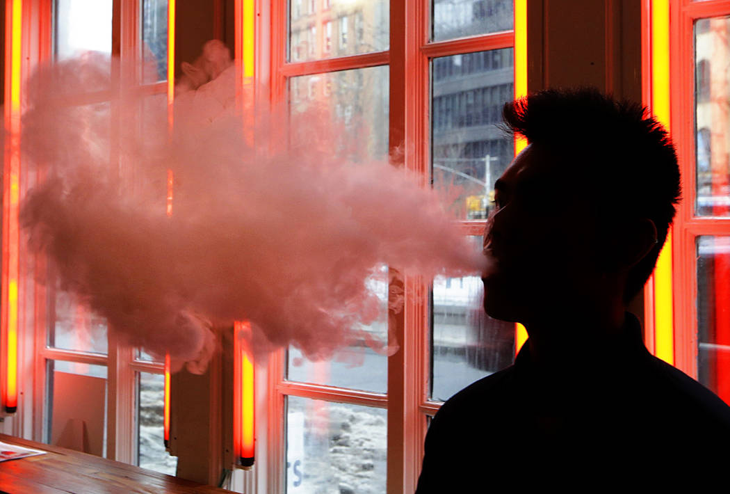 In a Feb. 20, 2014, file photo, a patron exhales vapor from an e-cigarette at a store in New Yo ...