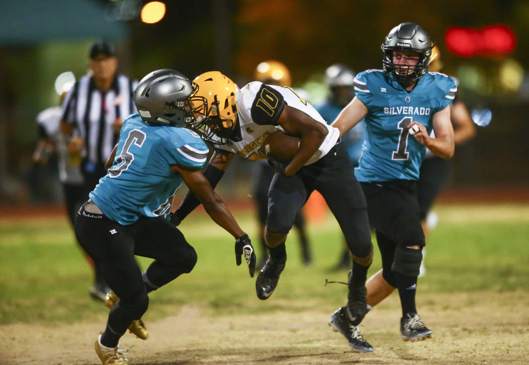 Clark's Dillan Lavender (10) gets stopped by Silverado's John Agounke (6) and Gregory Hunt (1) ...