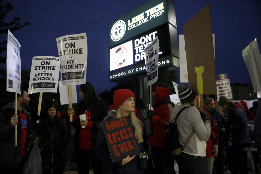 Striking teachers and supporters walk a picket line outside Lane Tech High School in Chicago, o ...