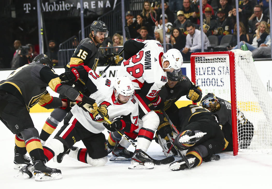 Ottawa Senators' Chris Tierney (71) and Connor Brown (28) try to get the puck in against the Go ...