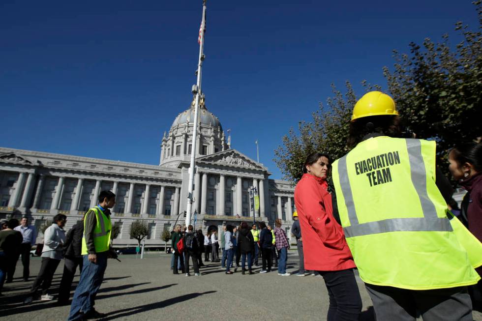 An evacuation team member stands with participants during an earthquake preparedness drill acro ...