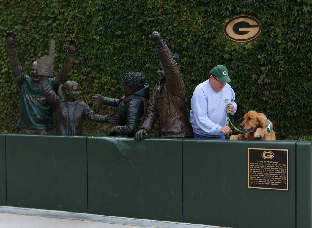 Packers season ticket holder John Nienaber, of Lakeside Park, Ky., tries to get his golden retr ...