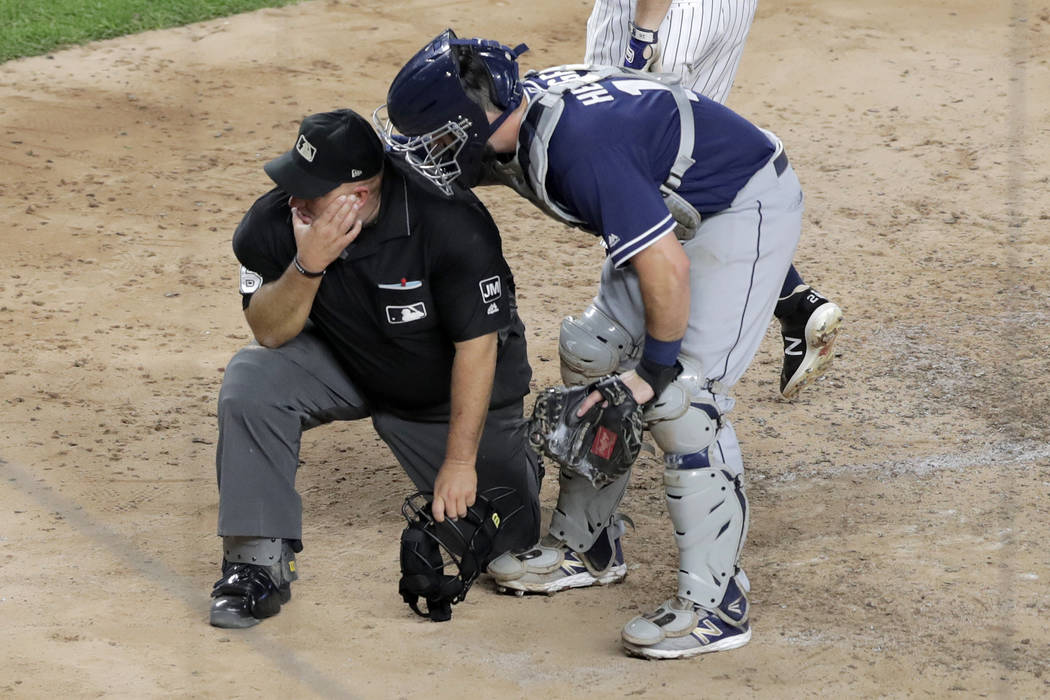 San Diego Padres catcher Austin Hedges, right, checks on home plate umpire Eric Cooper after th ...