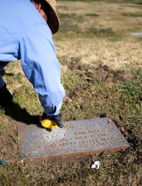 An employee at Palm Eastern Cemetery uncovers the overgrown gravestone of Jay Sarno on Monday, ...