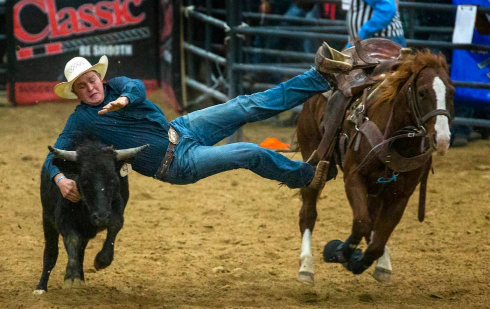 Steer wrestler Tyler Byrne leans way over to grab the steer during the first round of the India ...