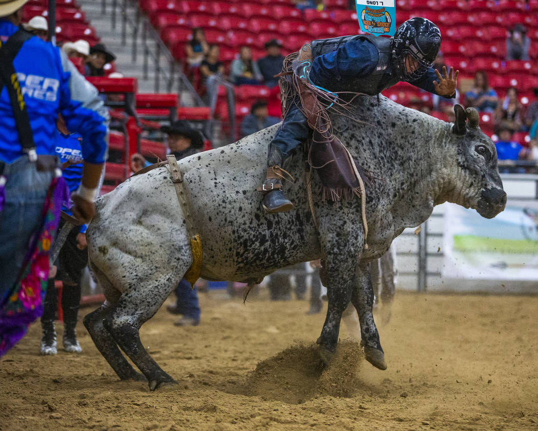 Bull rider Latrell Long is pushed forward but continues to hang onto his bull during the first ...