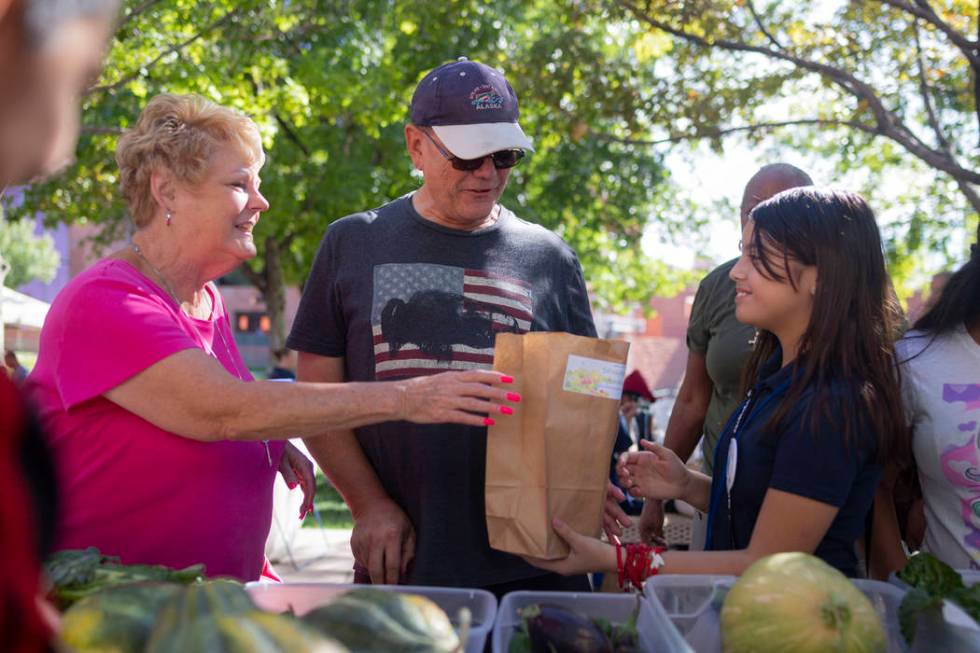 Local Las Vegas residents Cindy Smith, left, and Jeff Smith, center, purchase produce from Hele ...