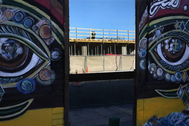 The construction site of an apartment complex is reflected through the glass door at the southw ...