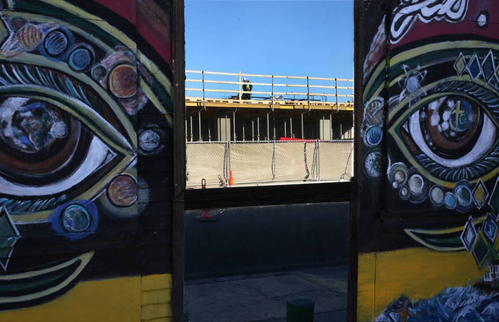 The construction site of an apartment complex is reflected through the glass door at the southw ...