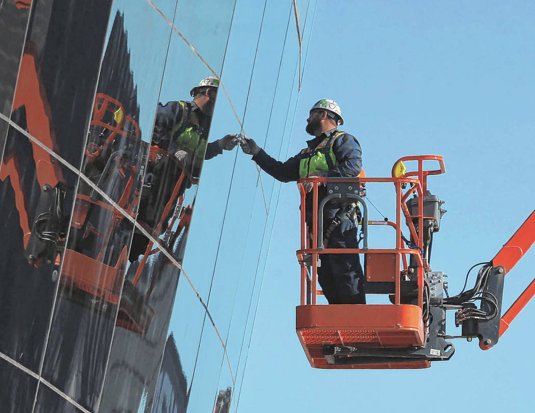 Workers check installed glass on the east side of the Raiders Allegiant Stadium in Las Vegas, T ...
