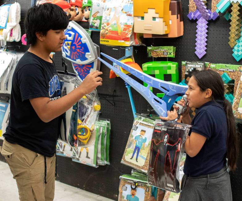 Luna Martinez, right, points a Halo gun at her brother D.J. Martinez, 13, at Spirit Halloween o ...