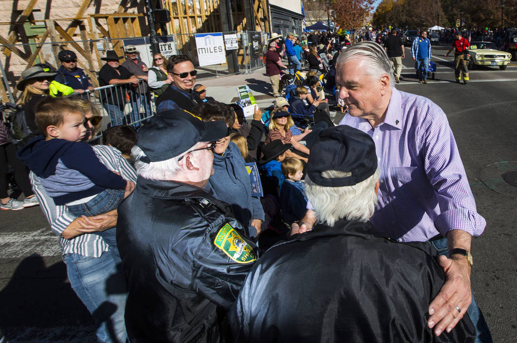 Gov. Steve Sisolak greets Dan Dulong, left, and Fred Webb, volunteers with the Carson City Sher ...