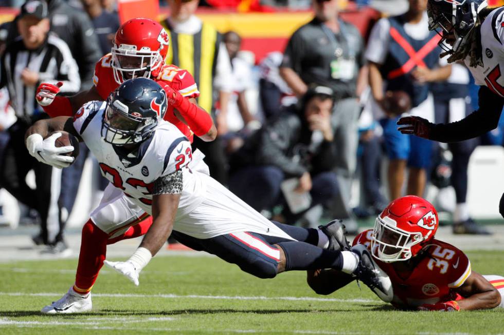 Houston Texans running back Carlos Hyde (23) is held back by Kansas City Chiefs cornerback Char ...