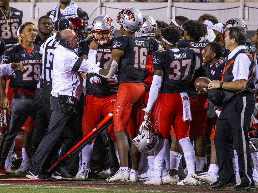 UNLV Rebels head coach Tony Sanchez attempts to control his offensive lineman Matt Brayton (72) ...