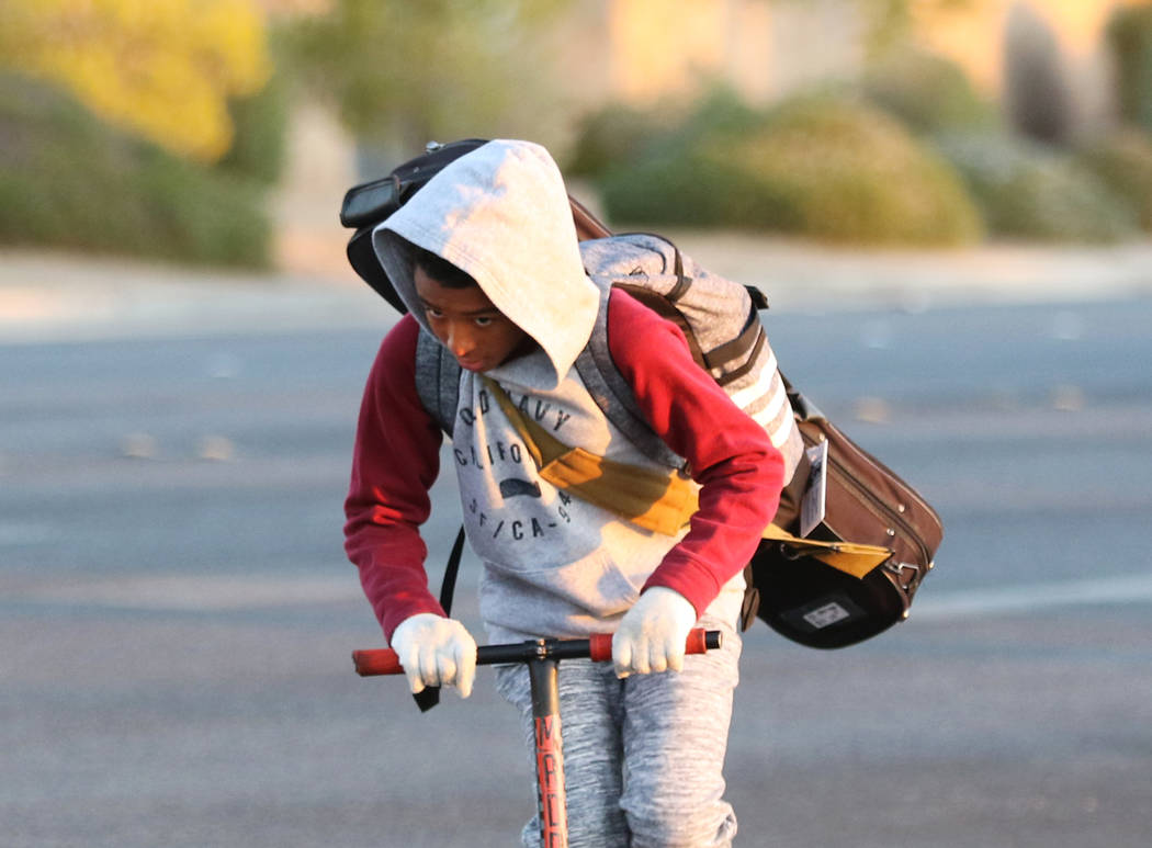 A boy is bundled up against the cold as he rides his scooter on Wednesday, Oct. 30, 2019, in He ...