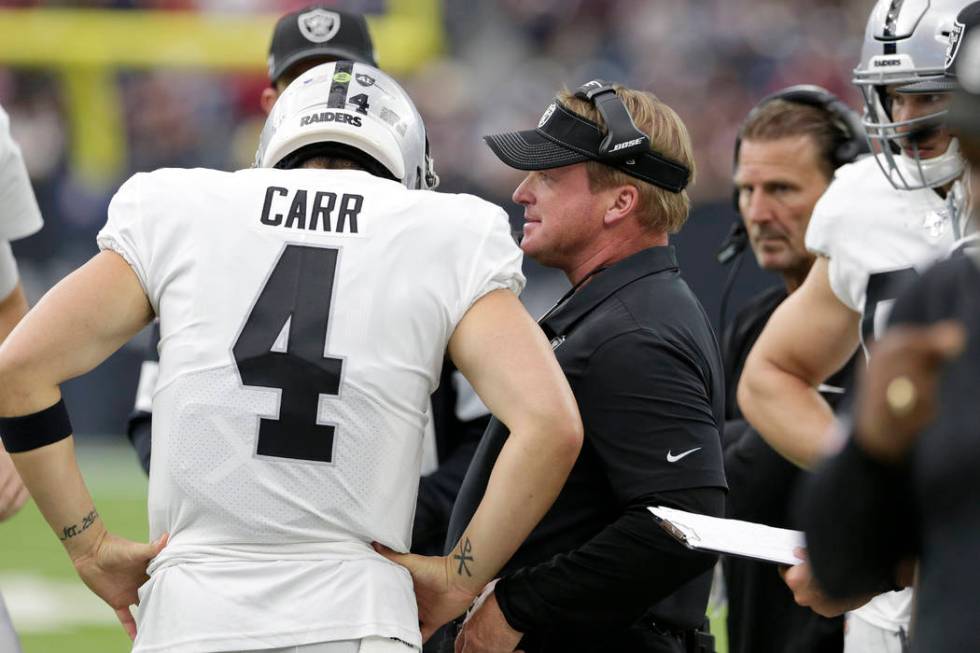 Oakland Raiders head coach Jon Gruden, center, talks with quarterback Derek Carr (4) during the ...