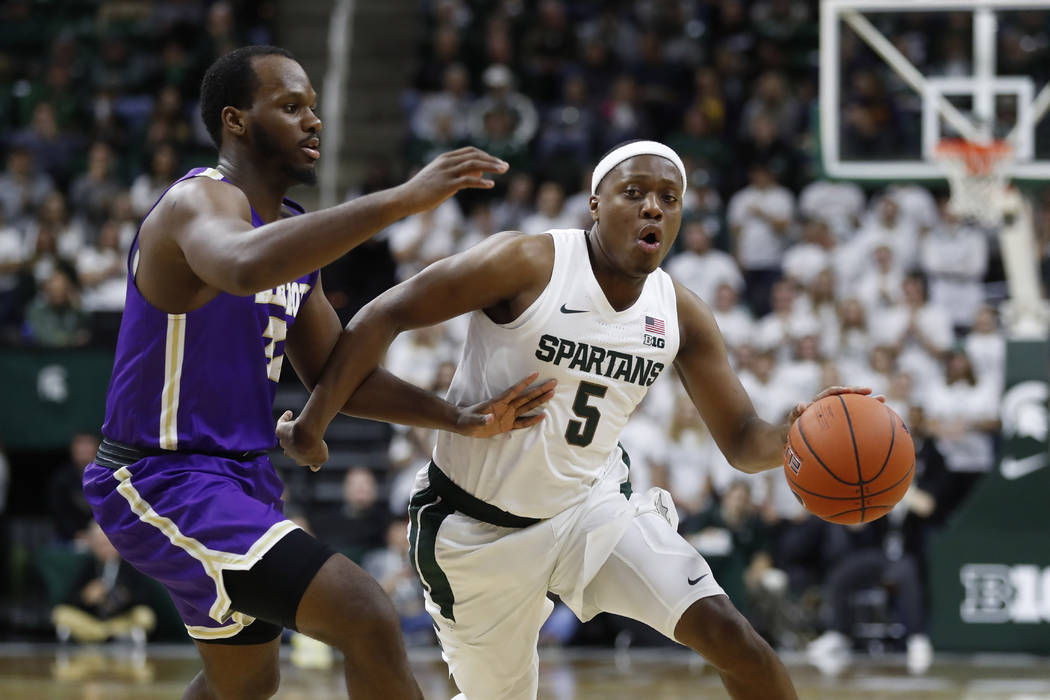 Michigan State guard Cassius Winston (5) drives on Albion forward Quinton Armstrong during the ...