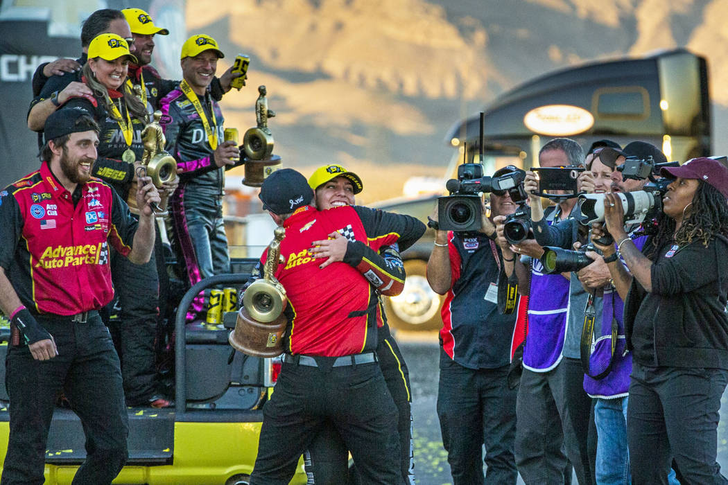 Top Fuel race winner Brittany Force hugs a crew member while carrying her trophy following the ...