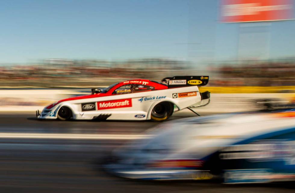 Funny car racer Bob Tasca III, left, takes the lead in the second round during the Dodge NHRA N ...