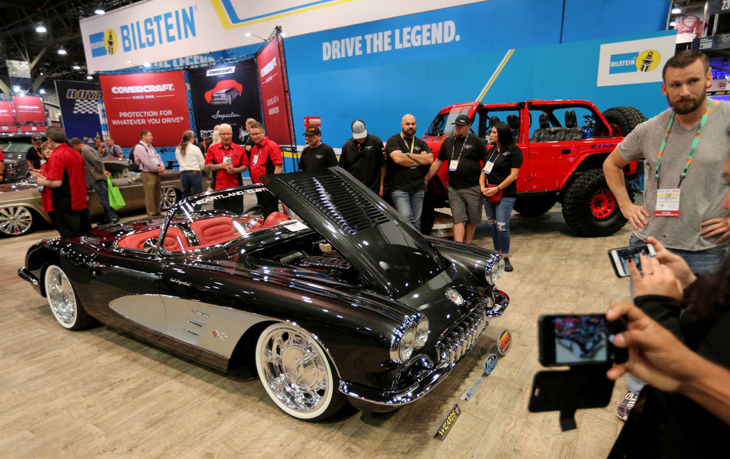 Conventioneers check out a 1958 Corvette at the Covercraft booth at the Specialty Equipment Mar ...