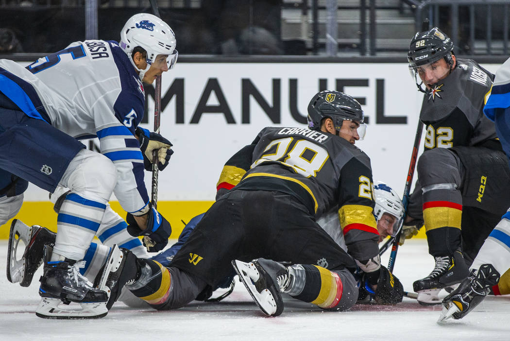 Vegas Golden Knights left wing William Carrier (28) sits atop of a Winnipeg Jets player during ...