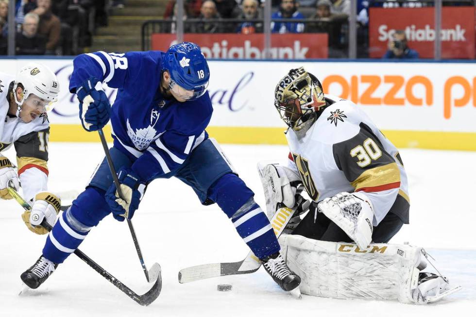 Toronto Maple Leafs center Mitchell Marner, back, watches as a goal by center John Tavares, goe ...