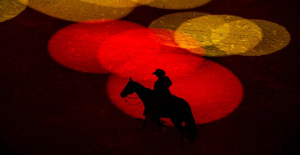 Safety man Derrick Begay is bathed in colored lights as during the opening ceremonies of PBR Wo ...