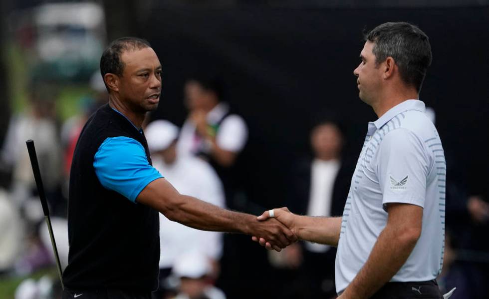 Tiger Woods of the United States, shakes hands with Gary Woodland of the United States on the18 ...