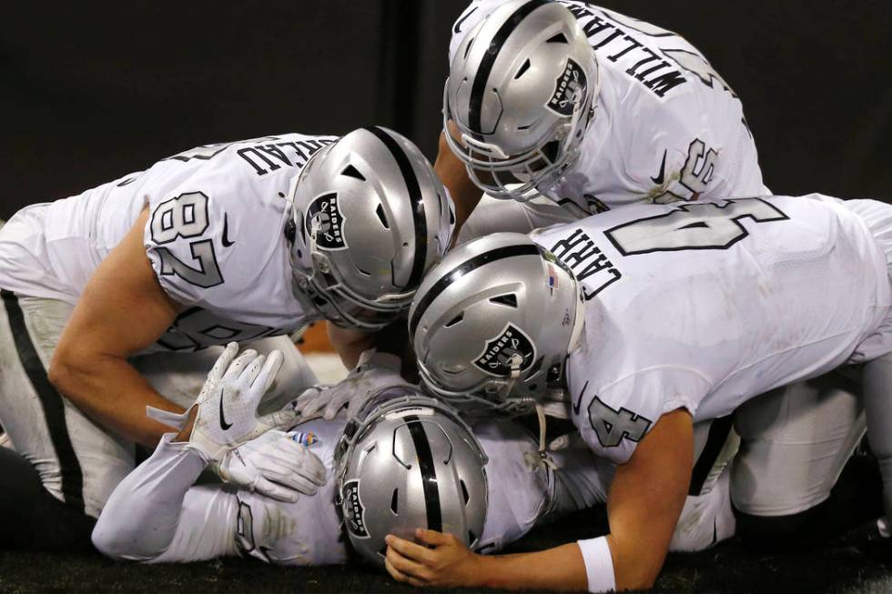 Oakland Raiders running back Josh Jacobs, bottom, is congratulated by teammates after scoring a ...