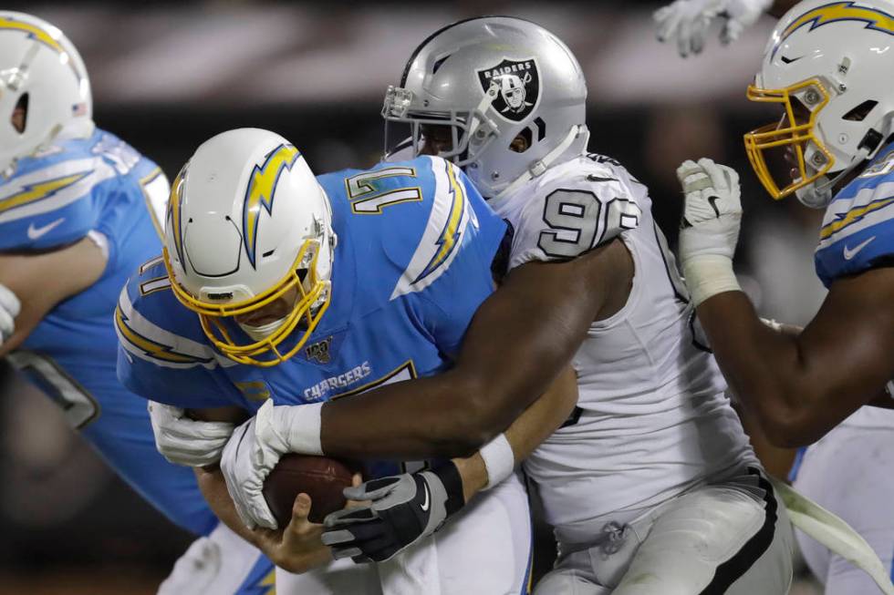 Los Angeles Chargers quarterback Philip Rivers (17) is tackled by Oakland Raiders defensive end ...