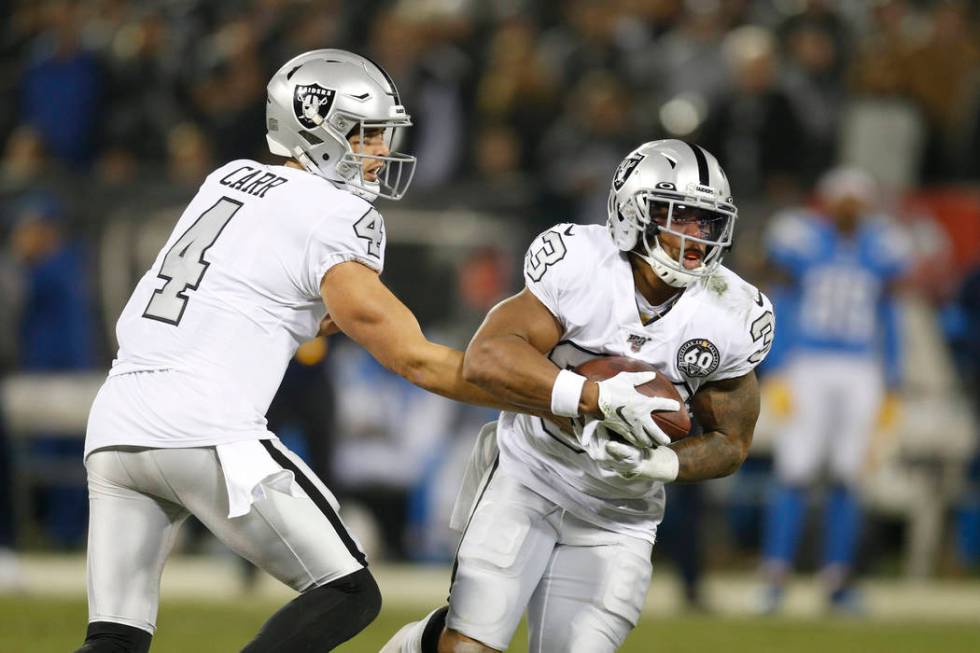 Oakland Raiders quarterback Derek Carr (4) hands off to running back DeAndre Washington (33) du ...