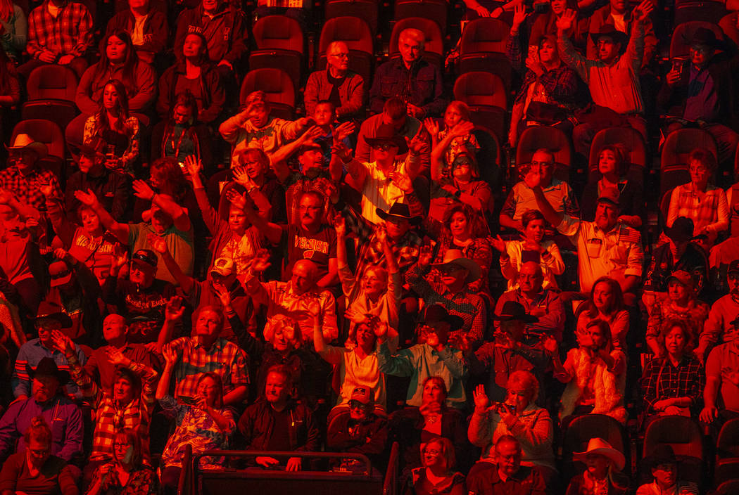 Fans are bathed in red as cowboys are announced during opening ceremonies on the third day of t ...