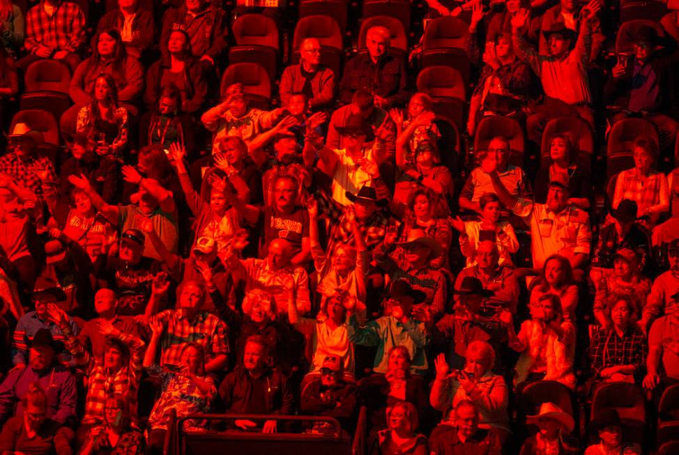 Fans are bathed in red as cowboys are announced during opening ceremonies on the third day of t ...