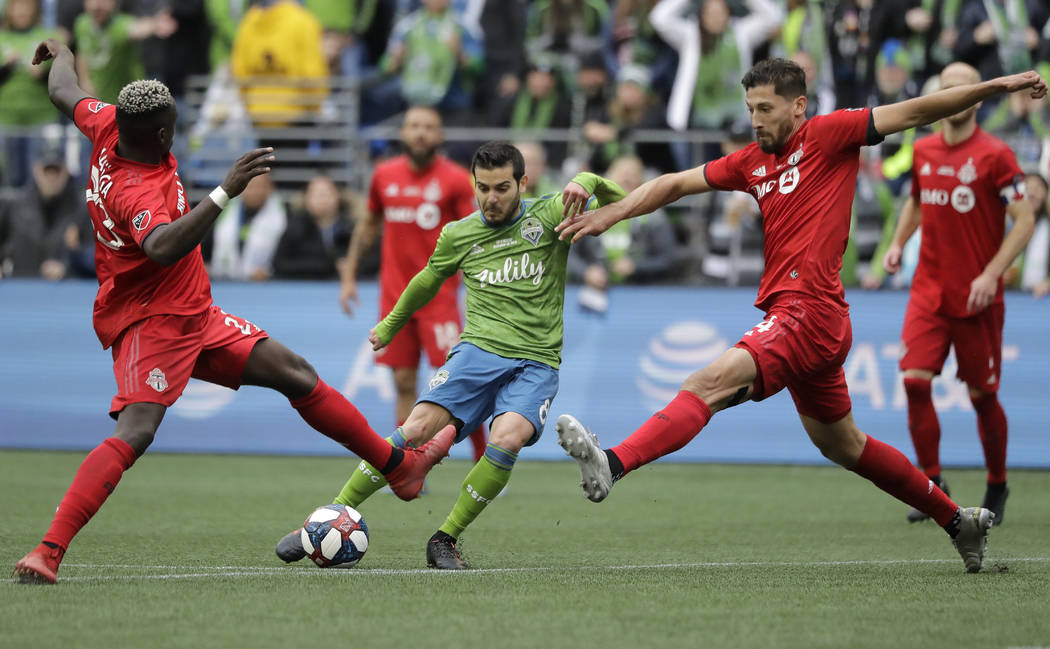 Seattle Sounders' Victor Rodriguez, center, kicks the ball to score between Toronto FC's Chris ...