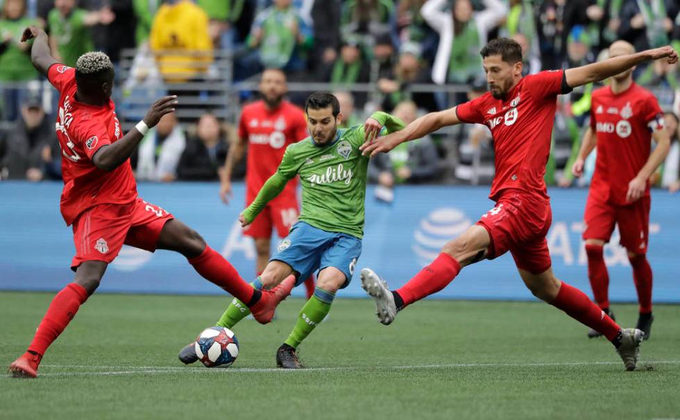 Seattle Sounders' Victor Rodriguez, center, kicks the ball to score between Toronto FC's Chris ...