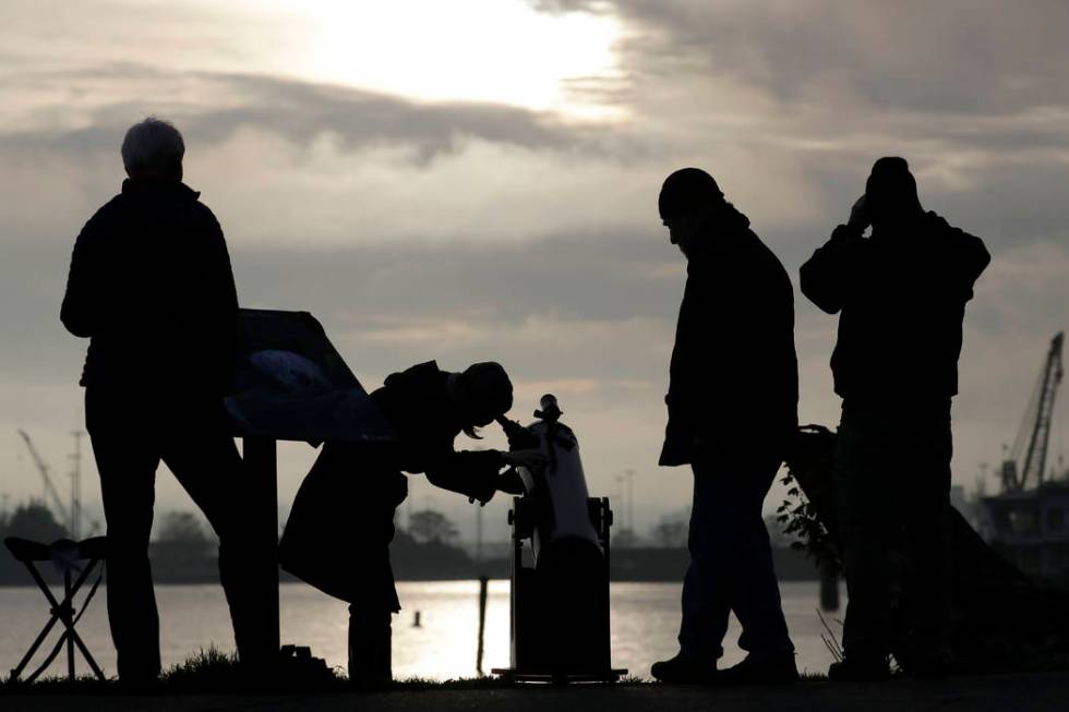 Viewers look on during a brief break in the clouds to see a transit of the planet Mercury as it ...